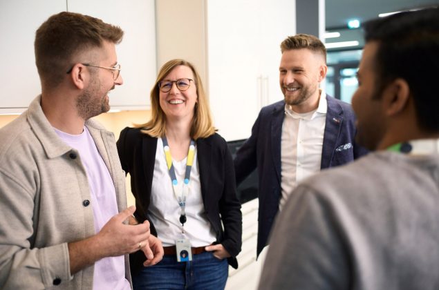 Vier Personen stehen zum Gespräch zusammen und haben Spaß