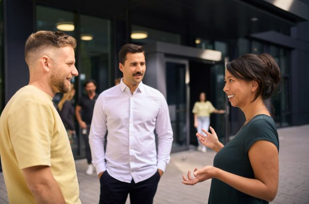 Zwei Männer und eine Frau stehen zu einem Gespräch zusammen
