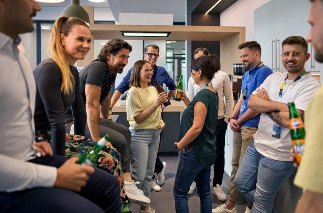 Eine Gruppe von Mitarbeitern stehen zusammen und trinken ein Feierabendbier